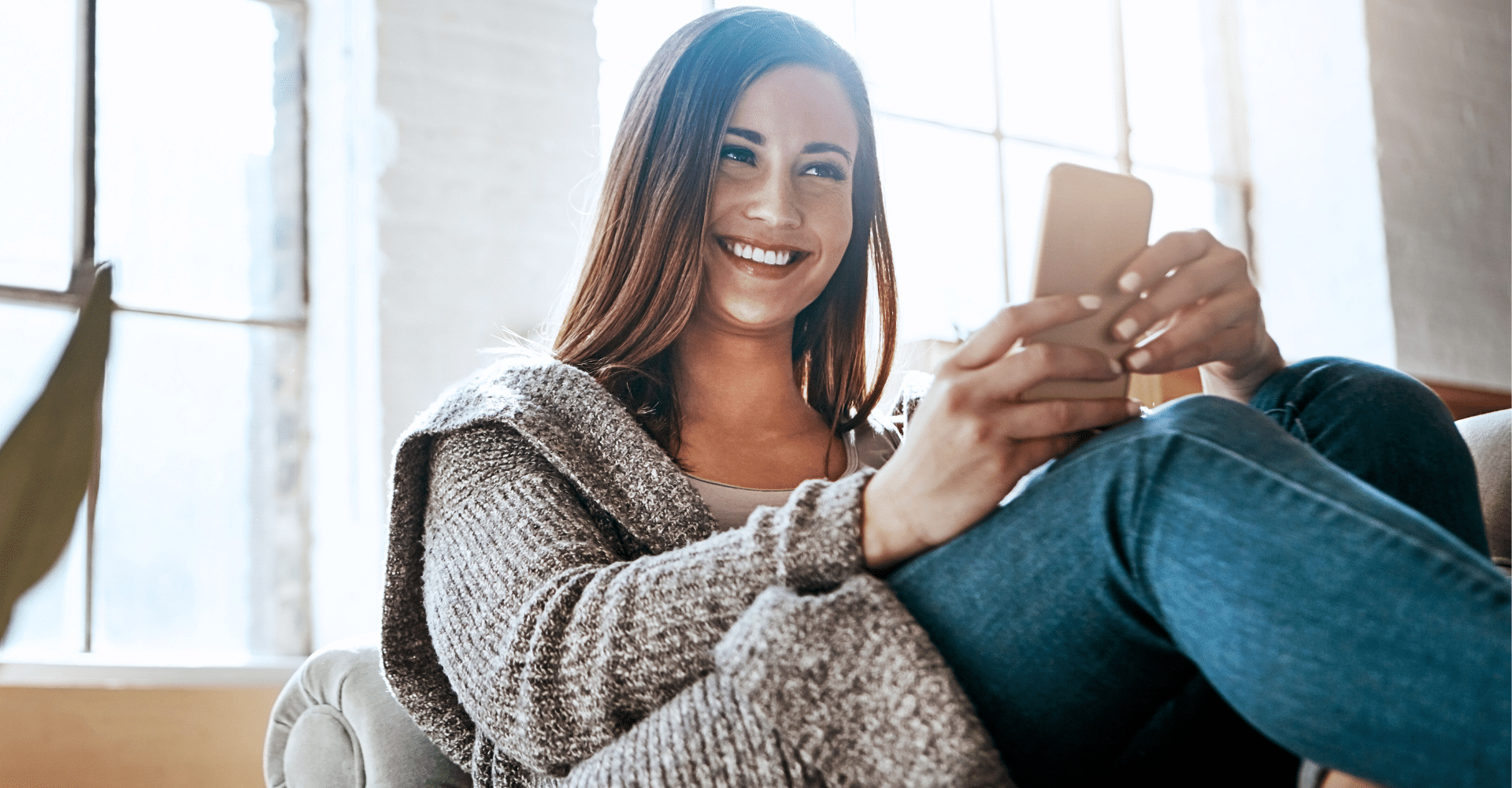 Woman sitting and laughing while holding a phone | Cedar Park Smiles