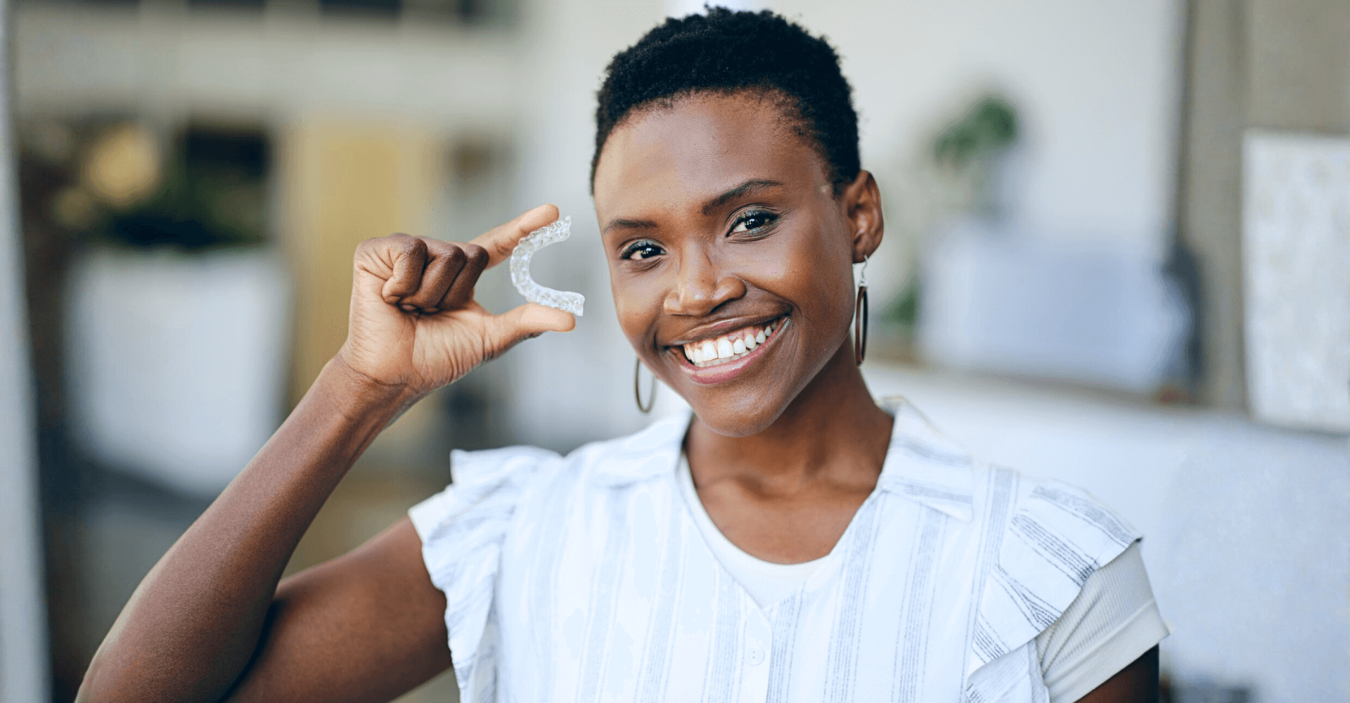 Woman holding up a clear aligner tray | Cedar Park Smiles